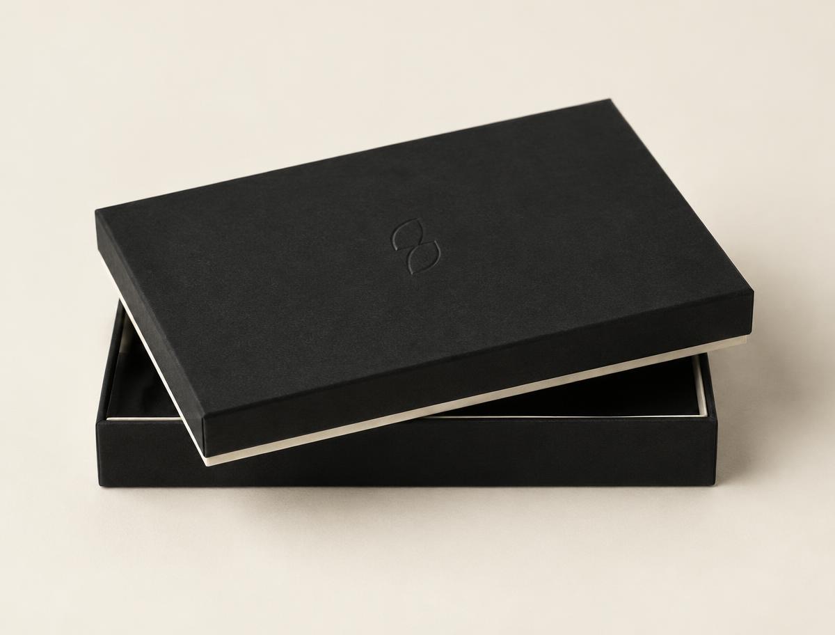 Small shallow rigid shoulder box in black wrap with an embossed mark